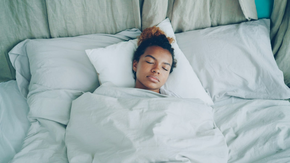 Woman sleeping peacefully in a white bed