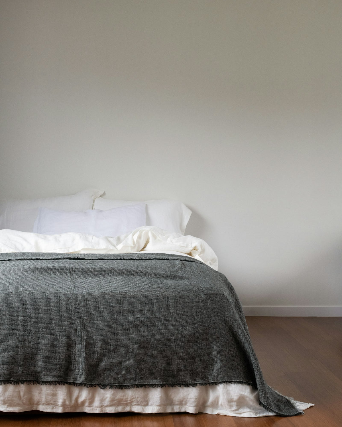 Neatly made bed with a soft grey blanket
